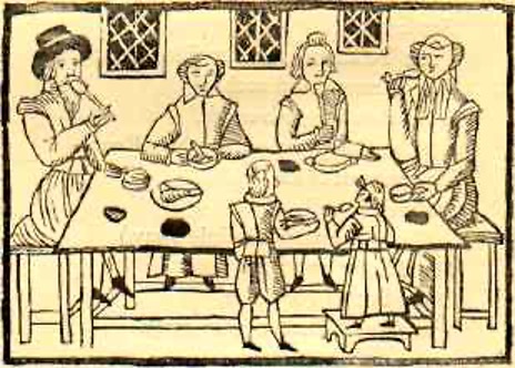 A print depicting a family sat around the dinner table. There is four adults on the far side of the table and two smaller figures representing children on the near side. One of the small figures, a girl in a dress, stands on a stool to reach the food. Various dishes are placed around the table.