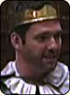 A photo of Paul Hopkins as the King of Gallia. He is a white man with dark brown hair and is wearing a golden crown.