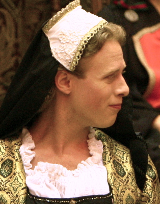 Matthew Krist as Gonorill. Gonorill is a white woman looking off to the side and smirking.