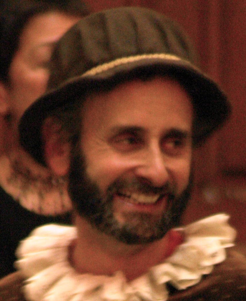 A photo of Alon Nashman as Mumford. He is smiling.